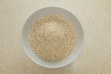 Top view oat flakes in white bowl, quick healthy breakfast on white marble table