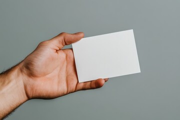 Obraz premium A confident hand elegantly presents a blank card against a serene gray background for creativity.