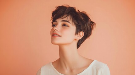 Obraz premium Young woman with short hair and a playful expression, standing against a pastel peach background, casual and carefree.