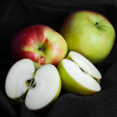 Sunrise apples against a dark background, including a halved apple to show the white interior of the fruit.