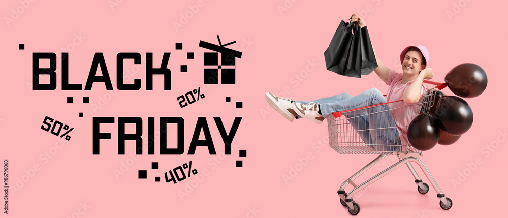 Canvas Prints Happy young man with bags and balloons sitting in shopping cart on pink background. Black Friday sale