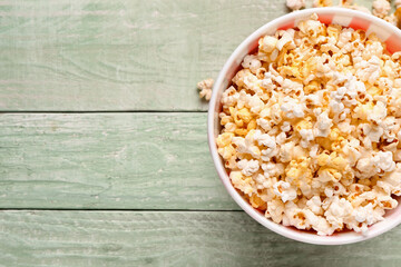 Bucket with tasty popcorn on green wooden background