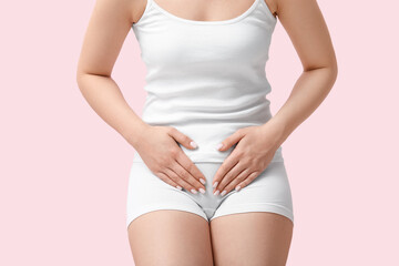 Young woman in underwear suffering from cystitis on pink background, closeup