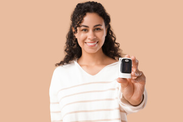 African-American woman with pulse oximeter on beige background