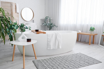 Interior of bathroom with bathtub, table and anti-cellulite scrub