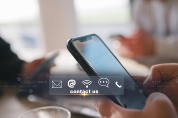 Contact us or Customer support hotline people connect. Businessman using a mobile phone with virtual screen contact icons email, address, live chat, internet wifi