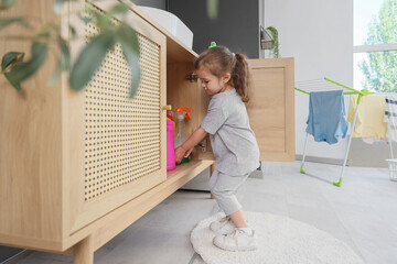 Cute little girl rummaging through drawer in laundry room. Child at risk