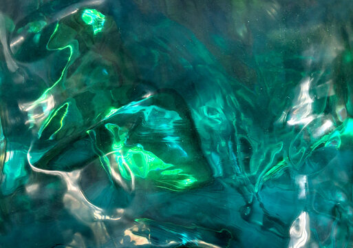Close up of emerald gemstone texture. Green tosca emerald stone contour, reflection. and refraction. Refractive effects from light dispersion on the gemstone surface.