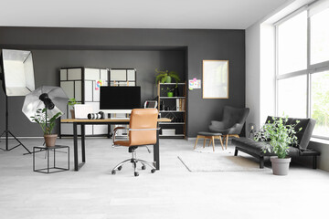 Photographer workplace with computer, laptop, photo camera and lighting equipment in modern studio