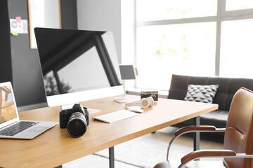 Photographer workplace with computer, laptop and photo camera in modern studio