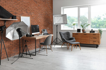 Photographer workplace with computer, photo cameras and lighting equipment in modern studio