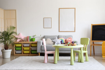 Interior of children's room with sofa, table and frames