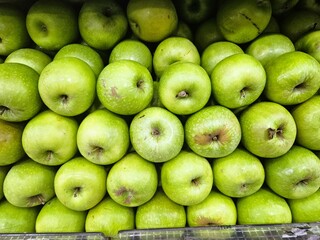 Green apples are neatly arranged on the shelf