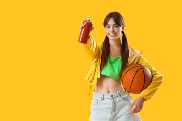 Young girl with spray can and ball on yellow background