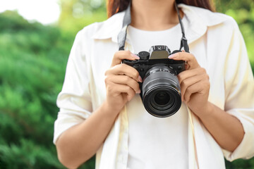 Female photographer with camera in park, closeup