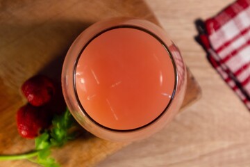 Top view of a glass of fresh strawberry juice on wooden table