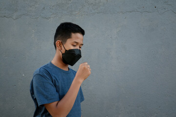 A teenager wearing a mask and coughing