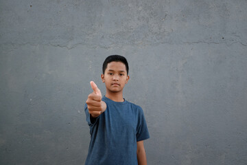 A teenager wearing a t-shirt giving a thumbs up