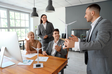 Group of engineers working with wind turbine model in office