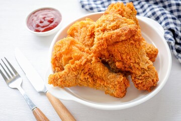 Fried chicken on a white plate with tomato sauce on white background