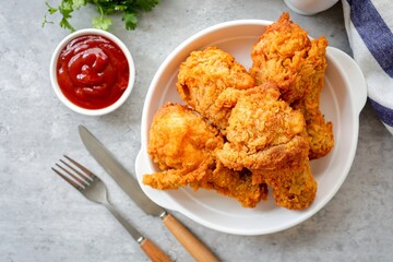 Fried Chicken Drumsticks in̈ white plate  with tomato sauce on gray cement  background, top view food table