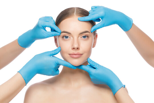 Portrait of young woman touched by doctors in blue gloves, preparing her for plastic surgery procedures