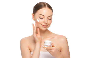 Young beautiful female with closed eyes applying face cream to cheekbones as part of morning routine