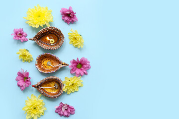 Diya lamps with flowers on blue background. Divaly celebration
