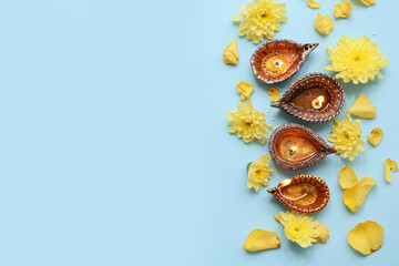 Diya lamps with flowers on blue background. Divaly celebration