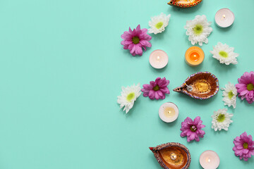 Diya lamps with flowers and candles on turquoise background. Divaly celebration