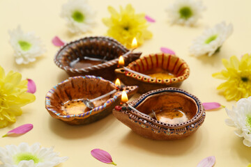 Diya lamps with flowers and petals on yellow background. Divaly celebration