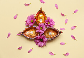 Diya lamps with flowers and petals on yellow background. Divaly celebration