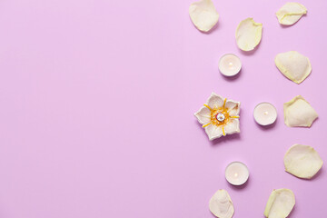 Diya lamp with rose petals and candles on purple background. Divaly celebration