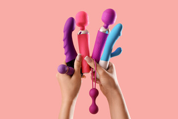 Woman with different vibrators and anal plug on pink background
