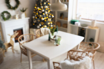 Blurred view of light dining room with table, fireplace and Christmas tree