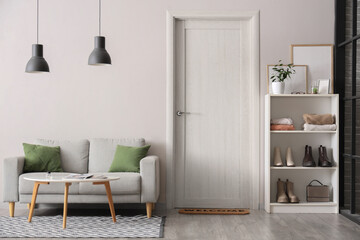 Sofa, coffee table and shelving unit with accessories in interior of hallway