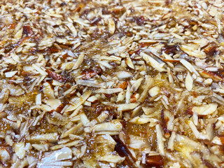 A close-up of intricately arranged, paper-thin almond slices delicately garnished on a cake reveals their fine, overlapping edges. 