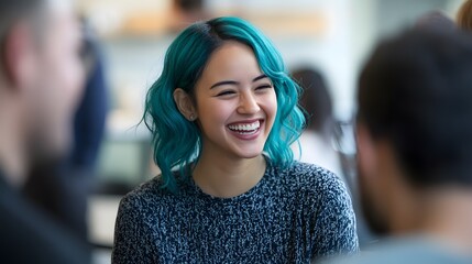 Fototapeta premium Happy female employee with teal hair laughing with colleagues in a relaxed office team-building induction meeting.