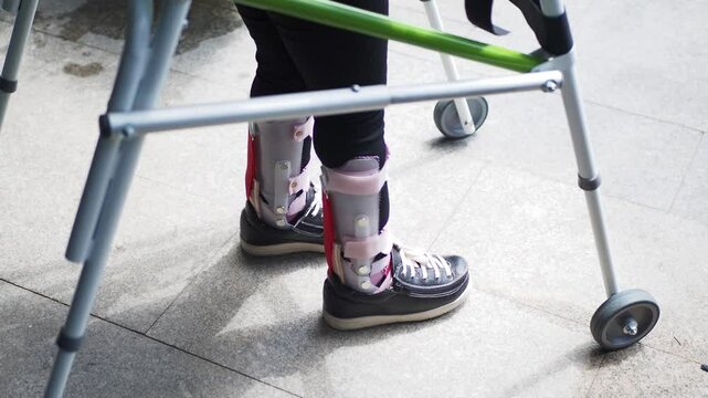  child with walking frame and knee orthosis outdoor 