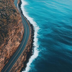 Fototapeta premium Aerial view of a coastal road winding along the ocean's edge.