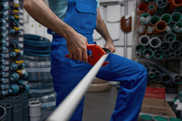 Salesman cutting pipe for client of plumbing hypermarket shop cropped shot