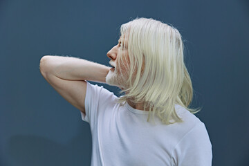 Portrait of a stylish person with long white hair against a solid blue background, showcasing a...