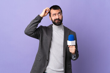 Adult reporter man with beard holding a microphone over isolated purple background having doubts while scratching head