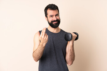 Naklejka premium Caucasian sport man with beard making weightlifting over isolated background inviting to come with hand. Happy that you came