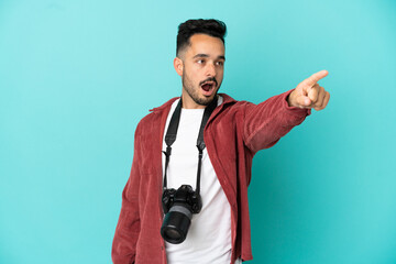 Young photographer caucasian man isolated on blue background pointing away