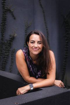 Woman with a smirk on her face in front of a grey and green wall.