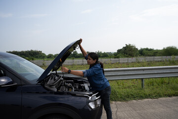 Young Indian girl on the road trying to fix her car after it's breakdown on road