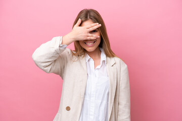 Young caucasian woman isolated on pink bakcground covering eyes by hands and smiling