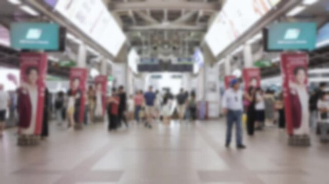 out of focus view on skytrain station platform with crowded of passenger changing train in rush hour while skytrain arriving and leaving from the station