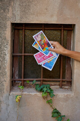 A hand with turquoise nails and a silver ring rests on scattered tarot cards, symbolizing...